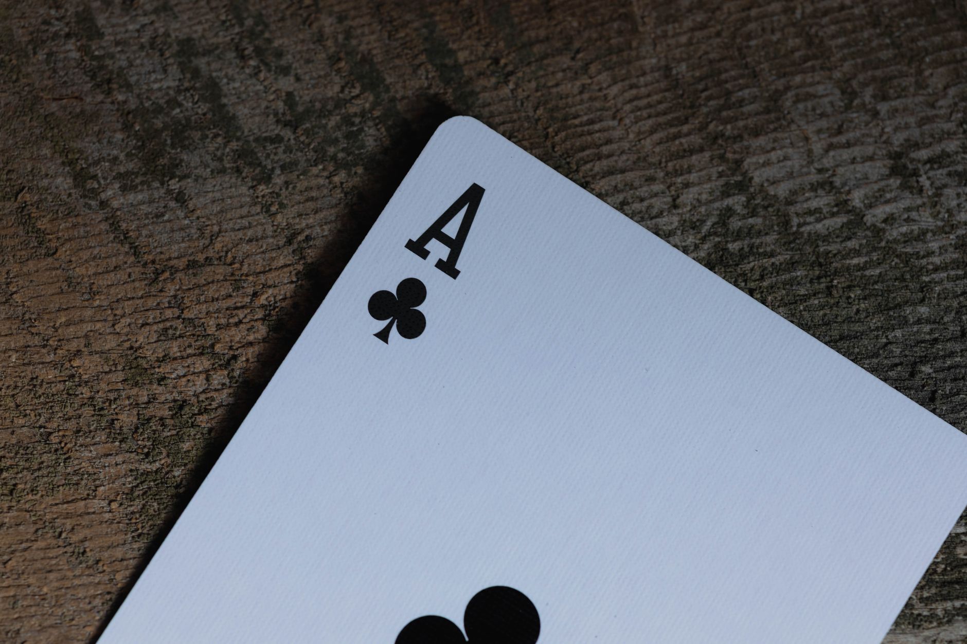 Ace of clubs playing card on a textured wooden surface, evoking a rustic and classic vibe.