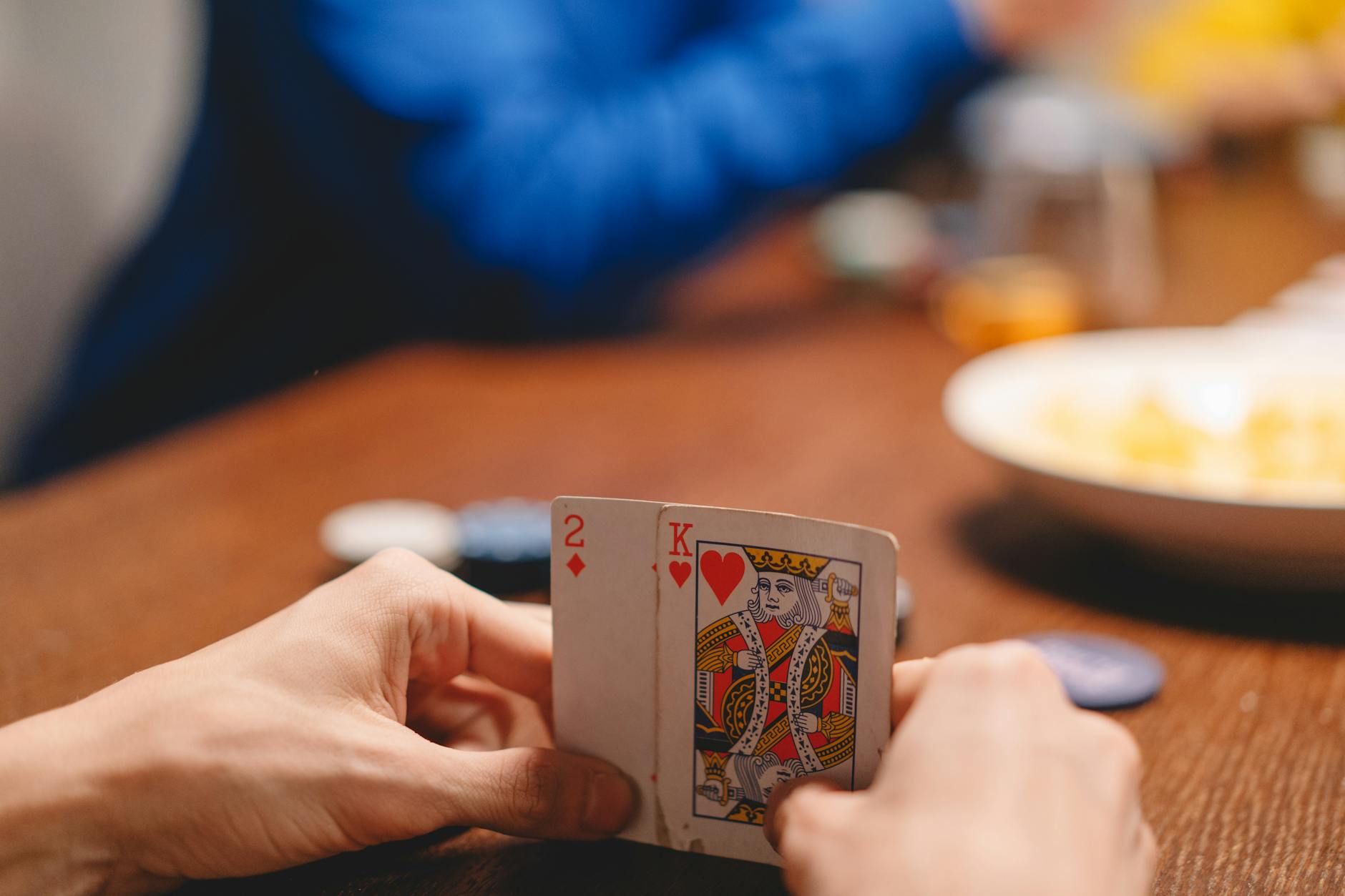 Close-up of a person holding playing cards during a poker game, focused on strategy and excitement.