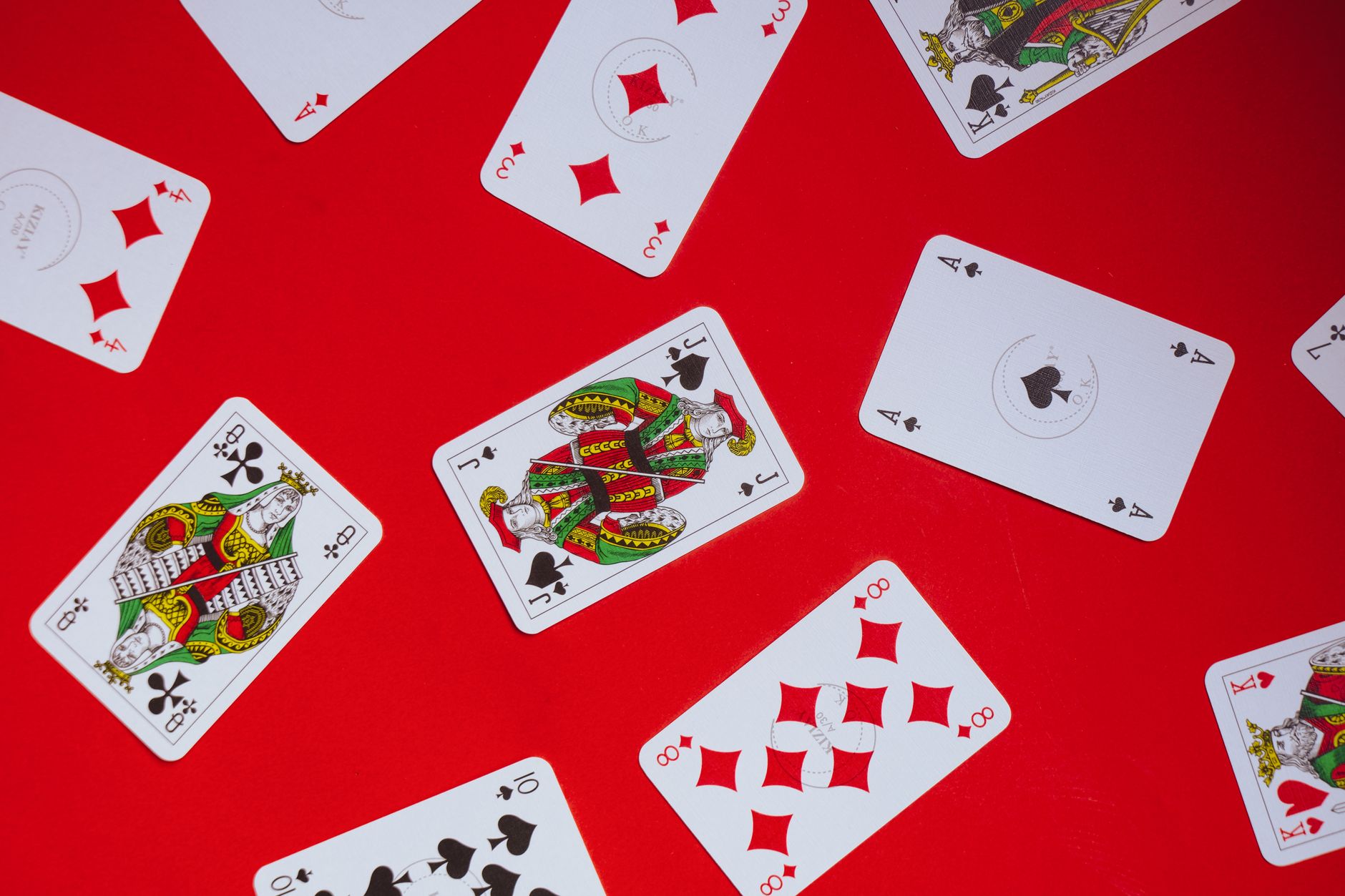 Scattered playing cards on a vibrant red background, perfect for themes of gaming and chance.
