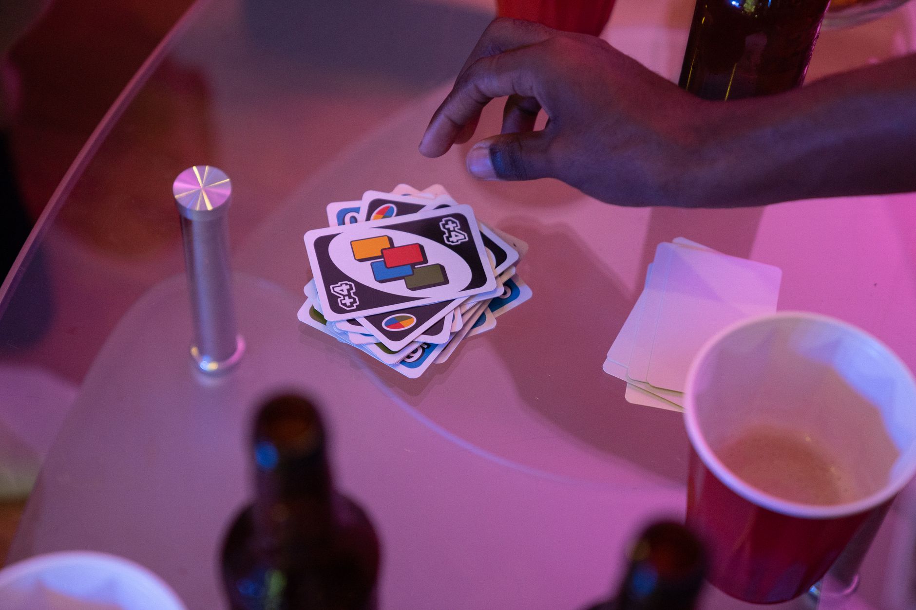 Close-up of a hand playing Uno cards on a table during a social gathering.