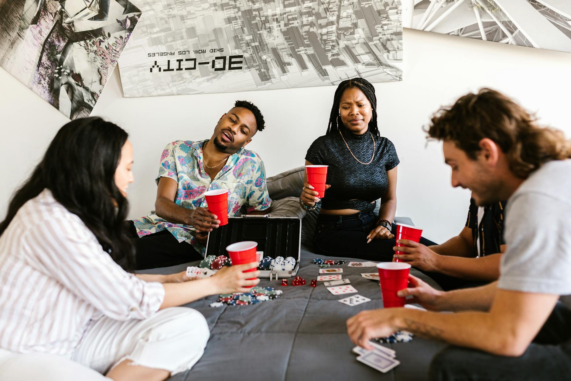 Group of diverse friends enjoying a poker game in a cozy indoor space with drinks.