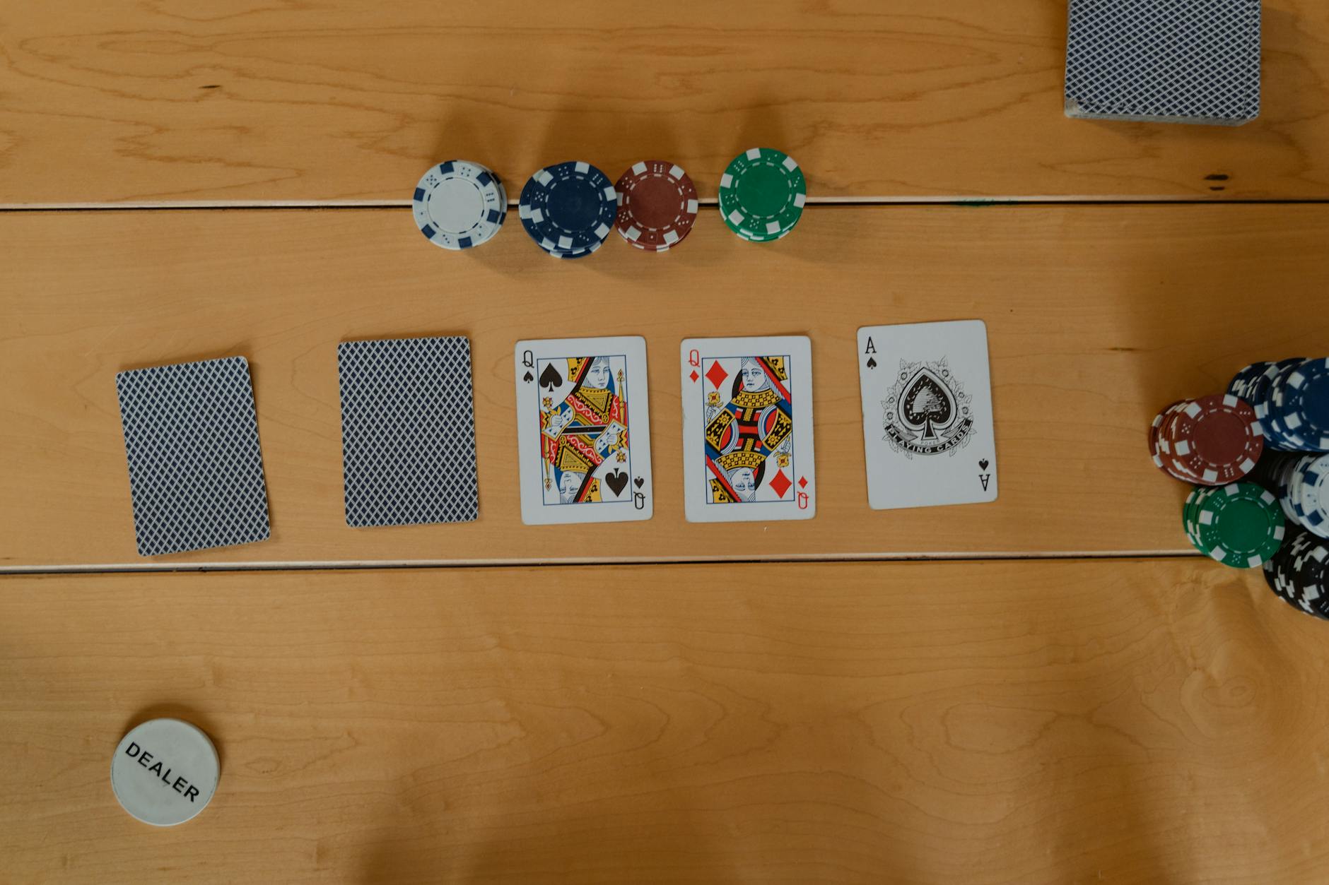 A poker game setup showing cards and chips on a wooden table, ready to play.