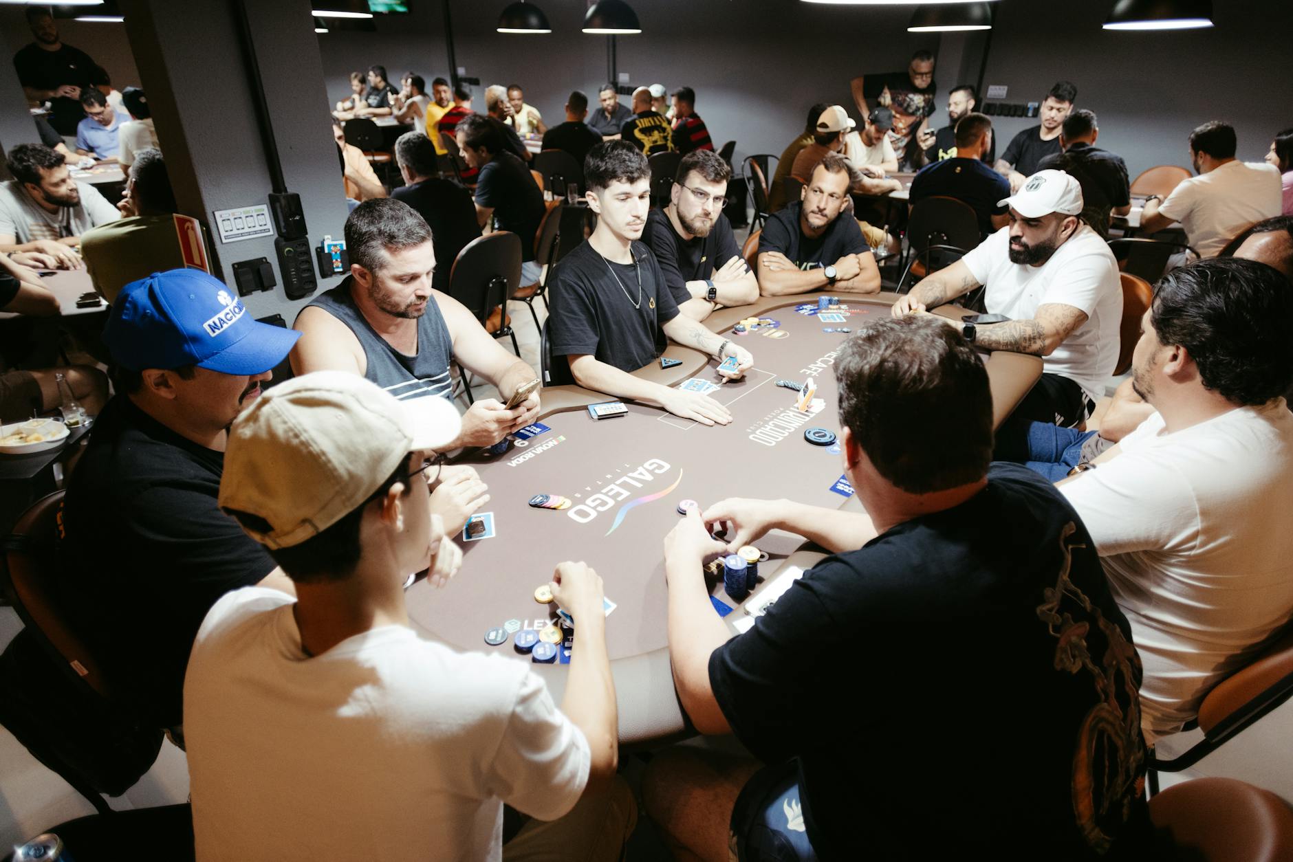 A group of adult men engage in a lively poker game at a vibrant casino setting.